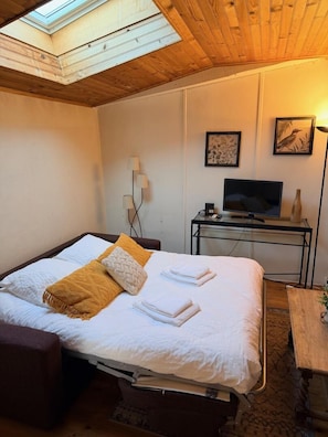 Una habitación de hotel con una cama, un escritorio con televisor, una lámpara y obras de arte en la pared.