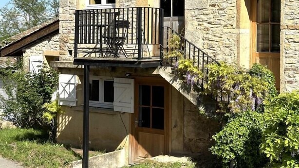 Un edificio in pietra con un balcone, una porta in legno e una finestra.