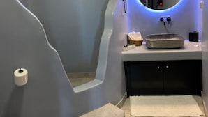 Ein Badezimmer im modernen Stil, mit einem großen Spiegel mit rundem Rahmen, einem kleinen Fenster und einem Waschbecken mit Waschtisch.
