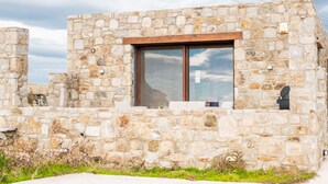 Ein Steinhaus mit einem großen Fenster und einer Holztür.