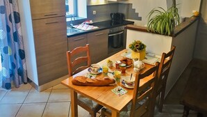 A compact kitchen with a dining area, wooden cabinets, a built-in stove, and a potted plant. - La Cadole - CHARNAY - Gîte (CHARNAY)
