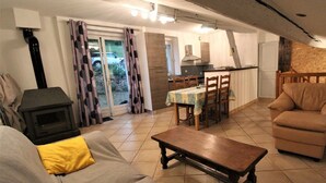 A cozy living room with a sofa, a coffee table, and a fireplace. There is a dining area with a table and chairs. - La Cadole - CHARNAY - Gîte (CHARNAY)
