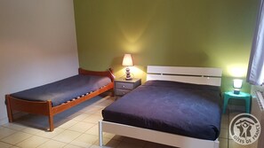 A bedroom with two single beds, a nightstand with a lamp, and a small table with a lamp.