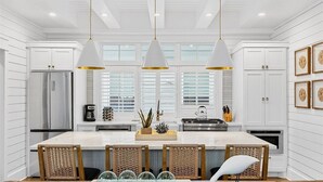 Een moderne keuken met witte kasten, een centraal eiland en hanglampen.