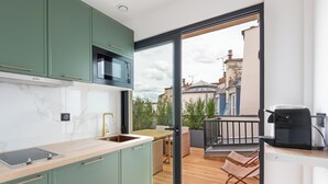 A modern kitchen with a built-in microwave, a sink, and a window overlooking a balcony with outdoor furniture. - Hotel au Coeur de Republique (Paris)
