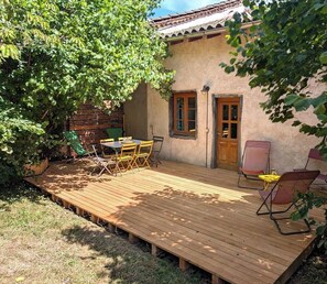 A wooden deck with a table and chairs, a door, and a window.