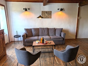 A cozy living room with a sofa, two armchairs, a coffee table with drinks, and wall-mounted lights.
