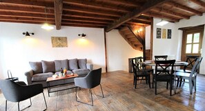 A cozy room with a wooden ceiling, a sofa, a coffee table, and a dining table with chairs.