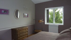 A bedroom with a bed, dresser, and a window with a view of trees. - La Colombière - SAINT-SYMPHORIEN-D'OZON (Saint-Symphorien-d'Ozon)