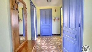 Un pasillo con suelo estampado, una puerta azul y un banco de madera.