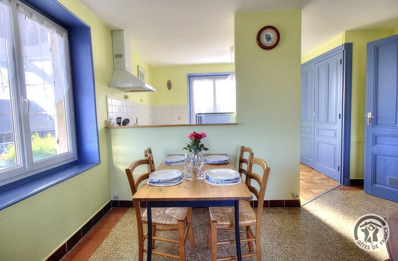 Un comedor con una mesa de madera dispuesta para cuatro personas, rodeado de sillas de mimbre.