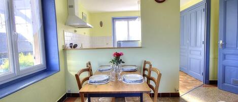 Un comedor con una mesa de madera dispuesta para cuatro personas, rodeado de sillas de mimbre.