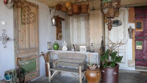 Un intérieur rustique agrémenté d’un banc en bois, de plantes en pot et d’objets de décoration d’époque.