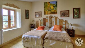 Une chambre avec deux lits, une grande fenêtre et différents éléments de décoration murale.