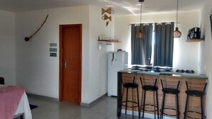 A modern kitchen with a central island, bar stools, pendant lights, and a refrigerator. - Flat1 Complete 5 minutes from the Taipu de Fora Swimming Pools (Marau)