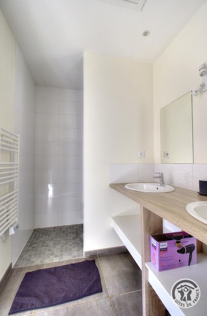 Un bagno moderno con lavandino bianco, specchio e zona doccia.