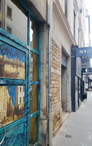 A building with a blue door featuring graffiti, a stone wall, and a sign for 'N°9 SHOW ROOM'.