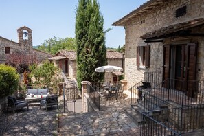 Un patio con suelo de piedra, mobiliario exterior y una torre de campanas.
