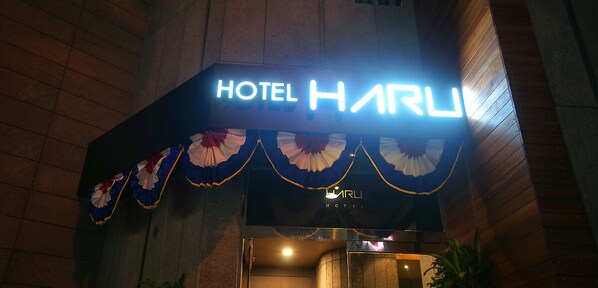 A hotel sign with the name "HOTEL HARU" and a decorative banner below it.