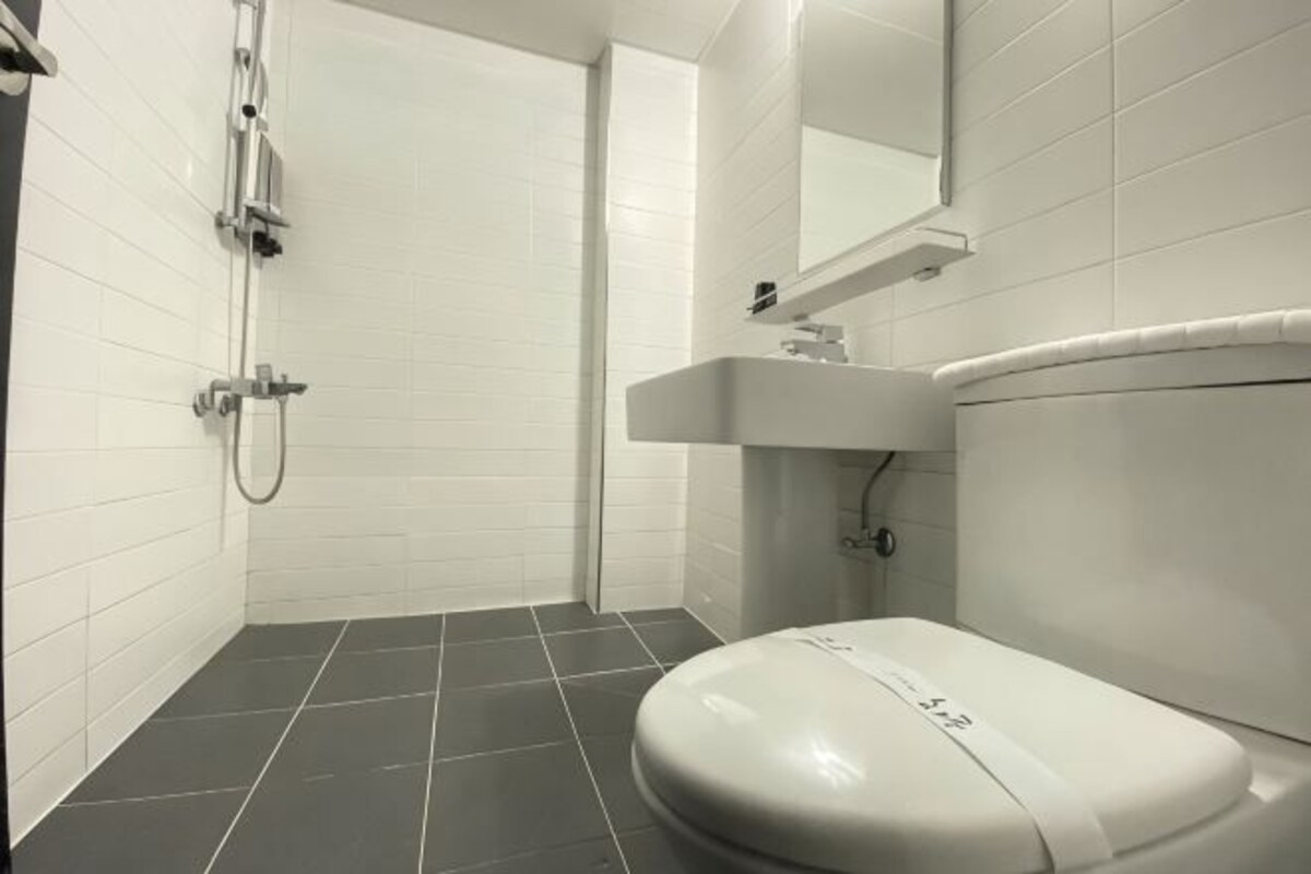 A modern bathroom with a white toilet, a shower, and a sink.