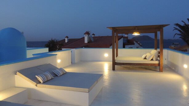 A rooftop terrace with a wooden canopy bed, a lounge area with cushions, and a view of the sea and buildings in the background. - Cozy Villa by MAHBO (A) (Corralejo)