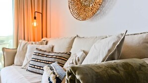 A beige sofa with patterned cushions, a woven wall decoration, and a wall-mounted light fixture. - Casa Grace (Nerja)
