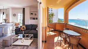 A living room with a sofa, coffee table, and a balcony with a view of the ocean. - Toboso 1 (Nerja)