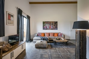 A modern living room with a sofa, ottoman, and a television on a wooden cabinet.