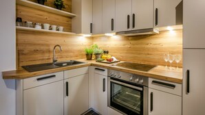 Una cocina moderna con armarios blancos, encimeras de madera, horno empotrado y un lavamanos.