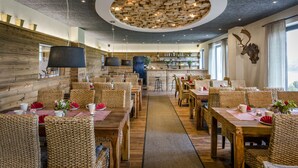 Un restaurante con paredes de madera, muebles de mimbre y un elemento decorativo en el centro del techo.