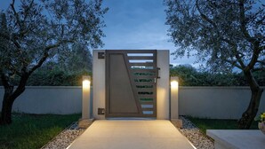 A modern gate with a metal barrier and a pathway leading to a building.