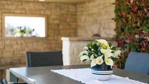 A dining table with a white tablecloth, a bowl of white flowers, and a potted plant with red and green foliage.