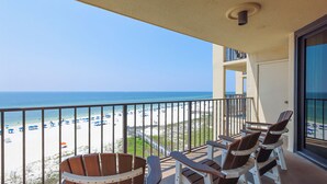Un balcon avec deux fauteuils Adirondack en bois, une vue dégagée sur la plage et une rambarde.