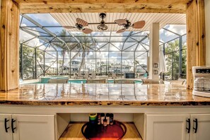 A kitchen with a large glass enclosure, ceiling fans, and a view of a pool area.