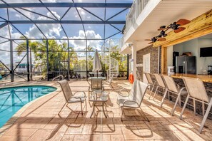 A poolside area with a glass enclosure, outdoor seating, and a bar area.