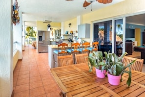 A spacious kitchen with modern appliances, a dining area with wooden tables and chairs, and a view of the outdoors. - Beach House, Waterfront, Sombrero Beach, Florida Keys Rental, Private Pool, Dock (Marathon)