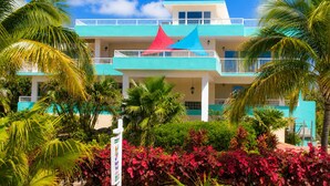 A multi-story hotel with a blue and white facade, a red and blue roof, and surrounded by tropical vegetation. - Beach House, Waterfront, Sombrero Beach, Florida Keys Rental, Private Pool, Dock (Marathon)
