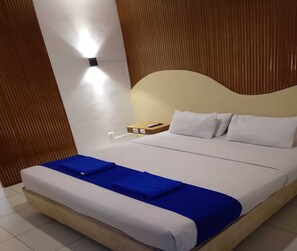 A hotel room with a bed, a bedside table, and a wall-mounted light. - Cozy Residence Cipedes Bandung (Bandung)