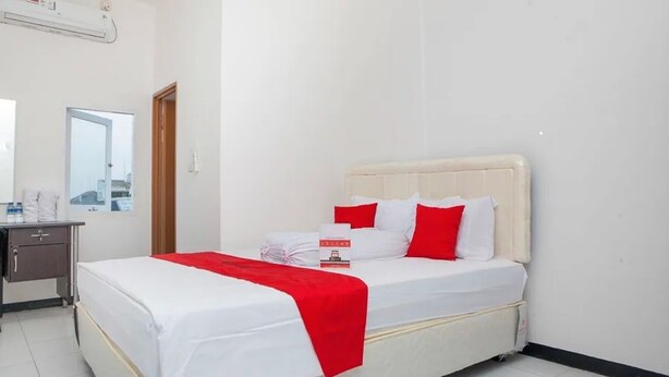 A hotel room with a bed, a bedside table, a mirror, and an air conditioning unit. - Cozy Residence Cipedes Bandung (Bandung)