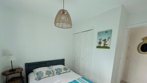 A bedroom with a bed, a bedside table with a lamp, a door, and a wall with a picture.