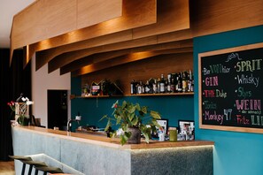 A bar area with a chalkboard menu listing drinks, a potted plant, and shelves with bottles. - Avenon Privat-Hotel am Steinberg (Roethenbach an der Pegnitz)