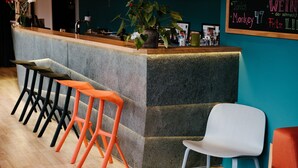 Una zona de bar con mostrador, taburetes y una planta en maceta.