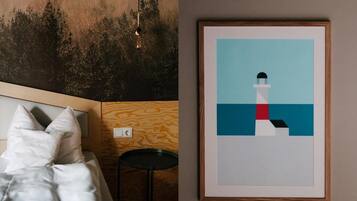 Un dormitorio con una cama, un cuadro enmarcado de un faro y una pared con un mural texturizado.