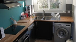 A compact kitchen with a dishwasher, washing machine, and a window providing natural light. - Town house on the banks of the vienne (Châtellerault)