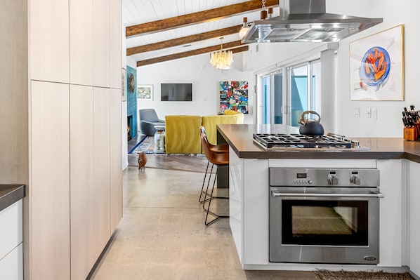 A modern kitchen with a built-in oven, a gas stove, and a stainless steel range hood. - On The Rocks – Tuscan-Moroccan Luxury Retreat (Palm Springs)