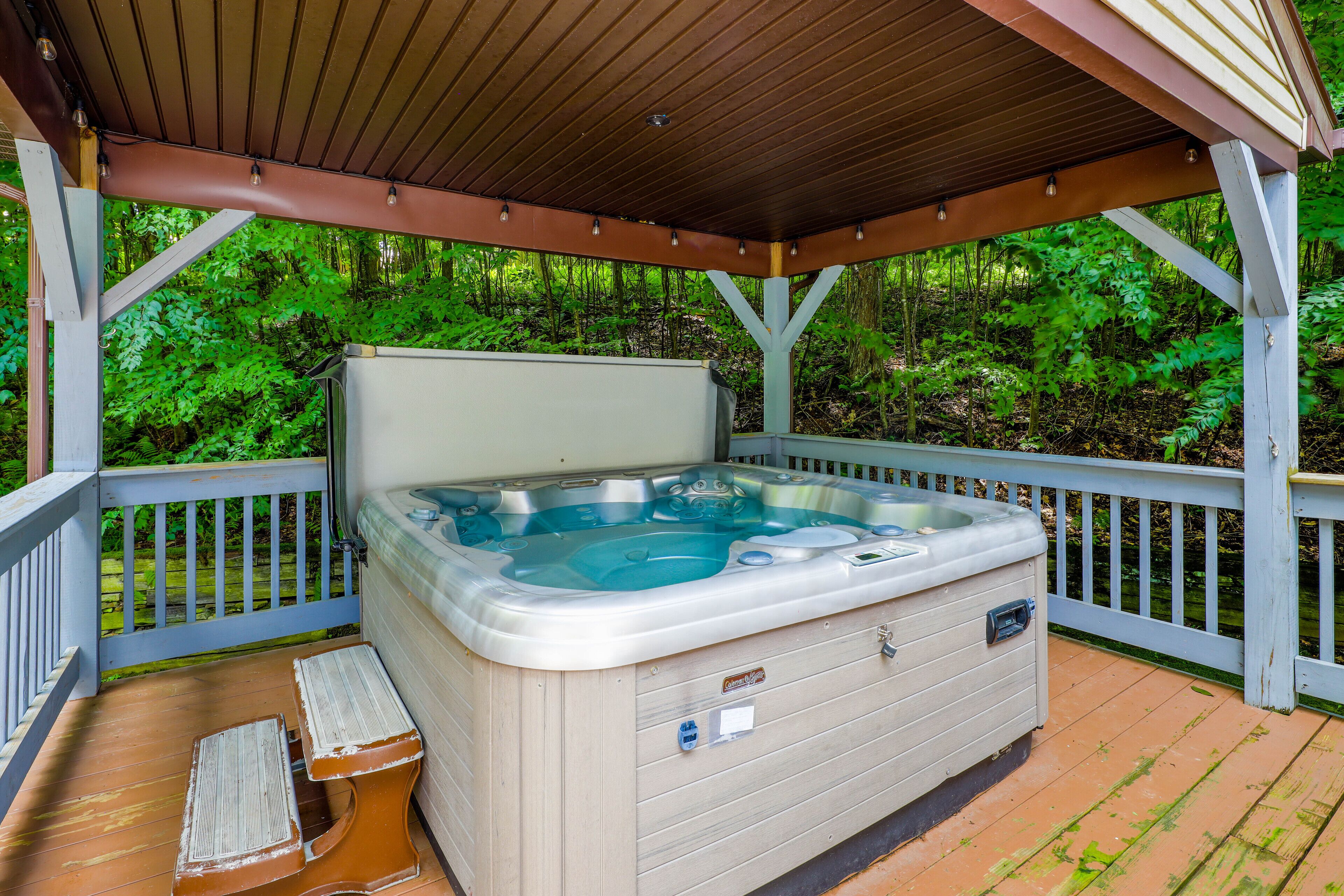 A hot tub on a wooden deck with a wooden pergola overhead.
