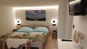 Una camera da letto con un letto, comodini, una TV e un quadro appeso al muro.