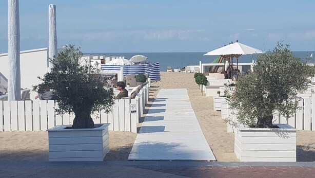 Un hotel sulla spiaggia con una passerella in legno che conduce alla spiaggia, zone relax all'aperto e vista sul mare.