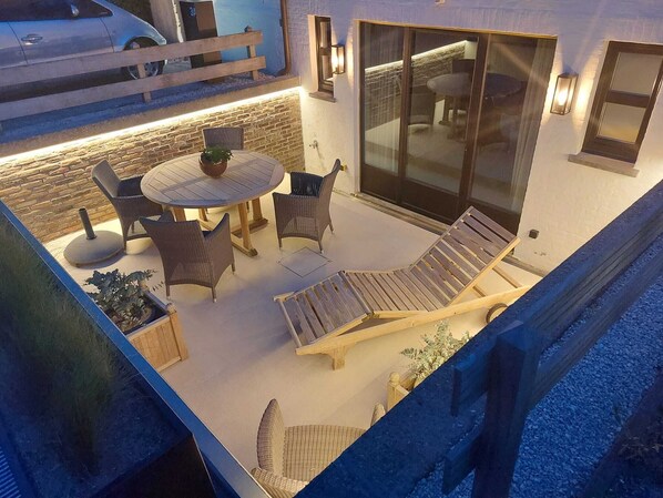 An outdoor patio with a round table, four chairs, and two lounge chairs.
