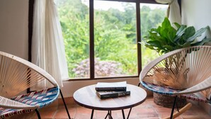 A room with two wicker chairs, a small round table, and a view of greenery through a window with curtains. - Portales del Tayrona Garden Hotel (Santa Marta)